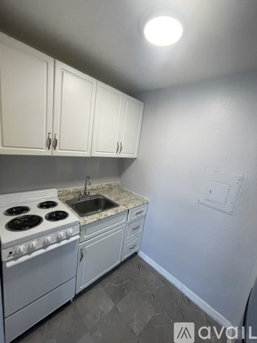 A kitchen with white cabinets and a white stove top oven.