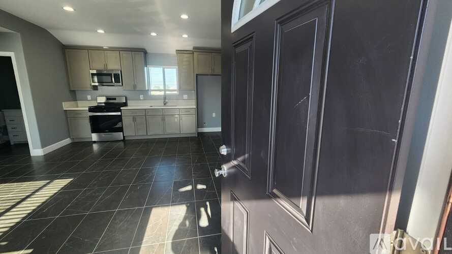 A kitchen with black cabinets and a black tiled floor.