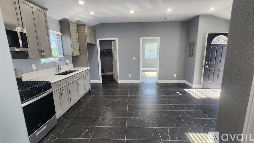 A kitchen with black tiles on the floor and a stove top oven.