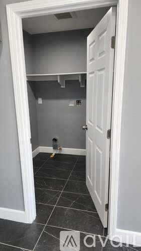 A white door is open to a small room with grey walls.