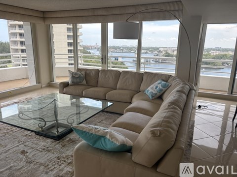 A living room with a beige couch and a glass table.