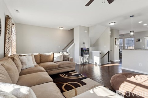A living room with a brown sofa and a black and white rug.