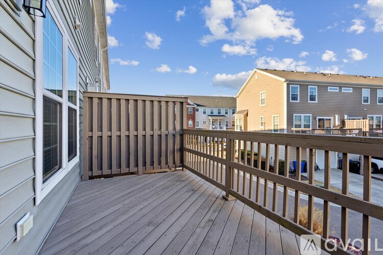 A wooden deck with a railing and a building in the background.