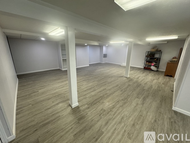A spacious room with wooden flooring and white walls.