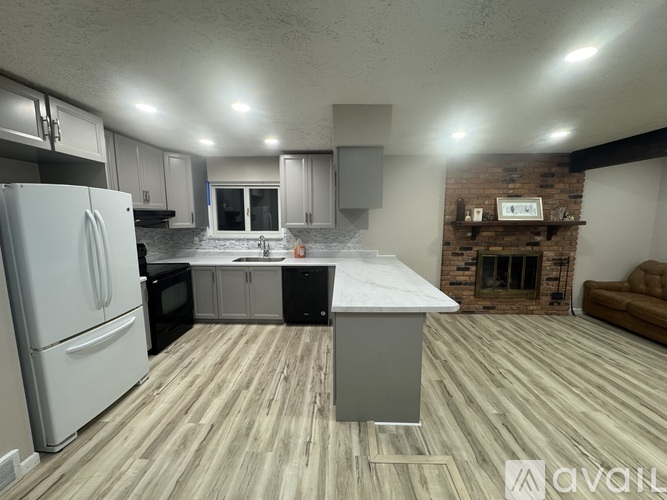 A kitchen with a white refrigerator and wooden flooring.