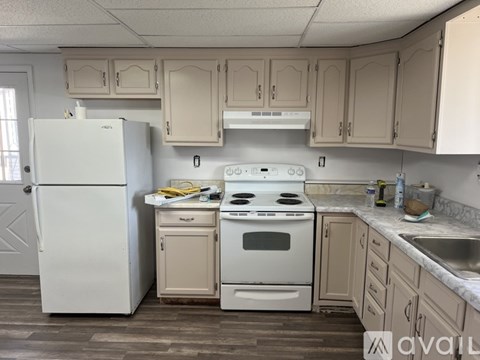 A kitchen with a white fridge, stove, and cabinets.