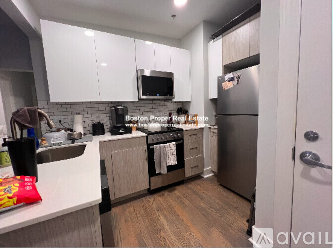 A kitchen with white cabinets and a stainless steel refrigerator.