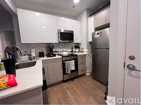 A kitchen with white cabinets and a stainless steel refrigerator.