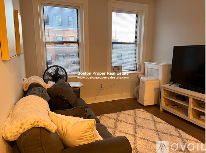 A person is sitting on a couch with a blanket in a living room.