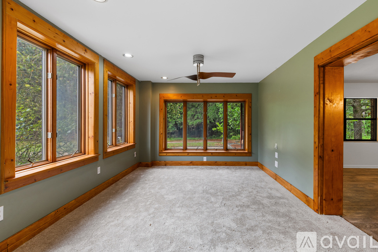 A spacious room with a ceiling fan and large windows.