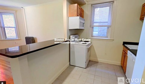 A kitchen with a white dishwasher and black countertops.