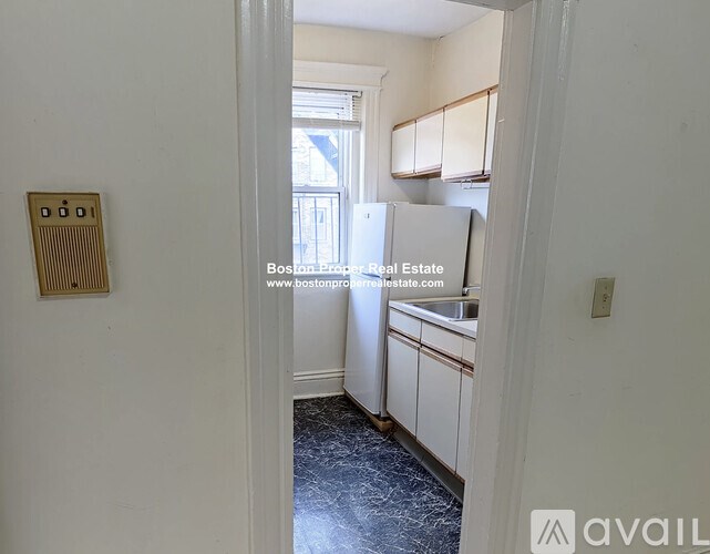 A kitchen with a refrigerator, sink, and cabinets.