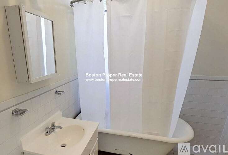 A white bathroom with a sink, mirror, and bathtub.