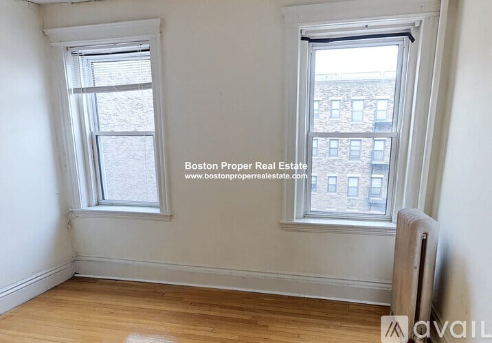 A room with two windows and wooden floors.