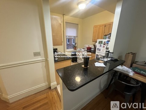 A kitchen with a black countertop and wooden flooring.