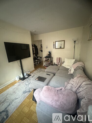 A living room with a grey couch and a flat screen TV mounted on the wall.