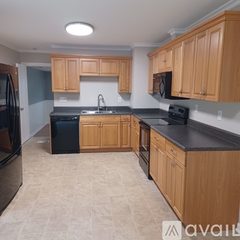 A kitchen with wooden cabinets and black countertops.