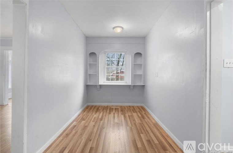A room with wooden floors and a window with a white frame.