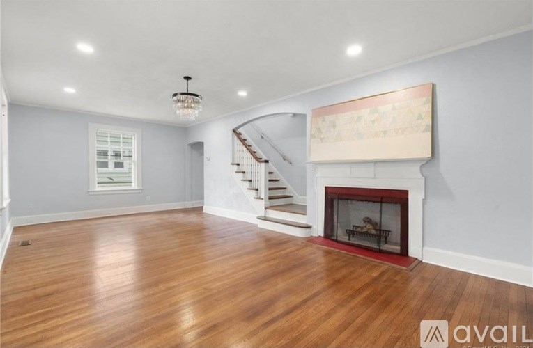 A spacious living room with a fireplace and a staircase.