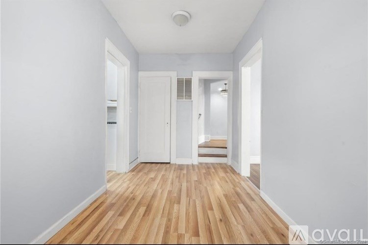 A hallway with wooden floors and white walls.
