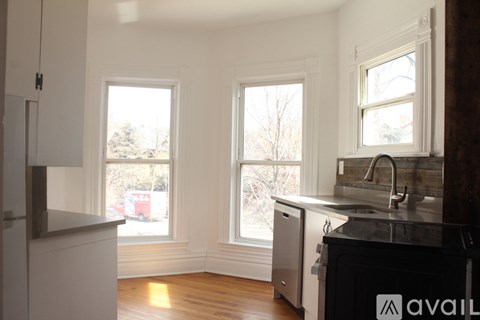 A kitchen with white cabinets and a black countertop is available for rent.