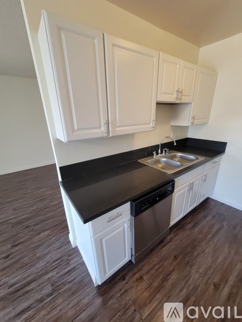 A kitchen with white cabinets and a black countertop.