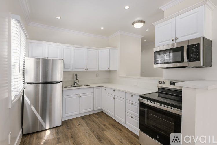 A kitchen with white cabinets and a stainless steel refrigerator.
