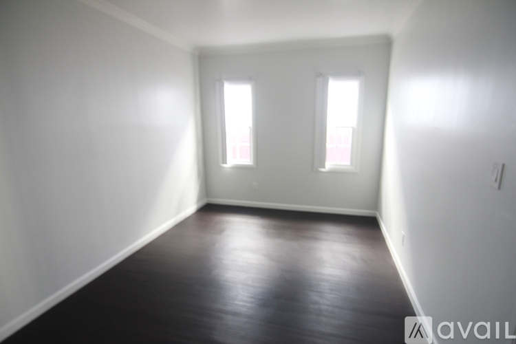 A spacious room with wooden flooring and a ceiling fan.