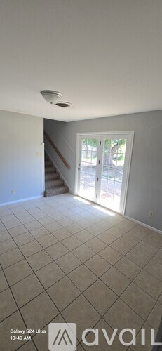 A room with a staircase and a door leading outside.