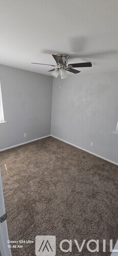 A room with a ceiling fan and carpeted floor.