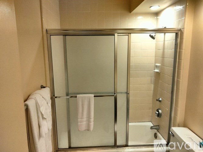 A white towel hangs on a glass door in a bathroom.