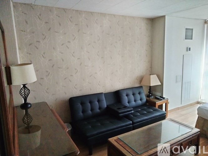 A black leather sofa sits in a room with a glass table in front of it.