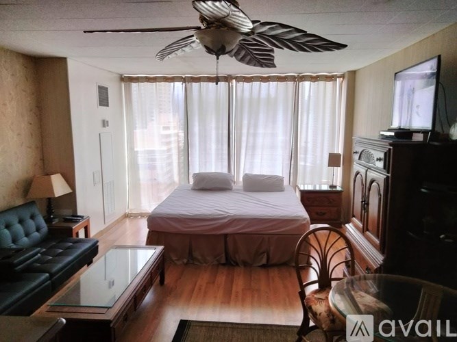 A bedroom with a bed, a chair, a dresser, and a ceiling fan.