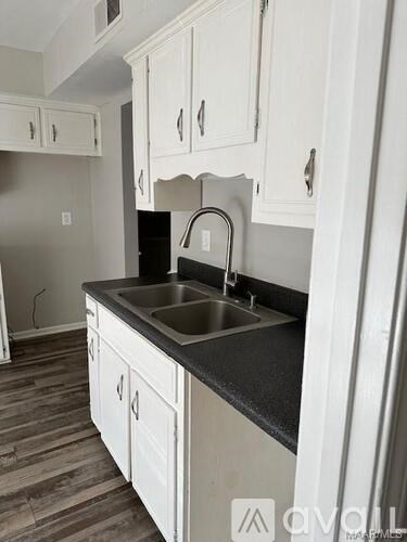 A kitchen with white cabinets and a black countertop.