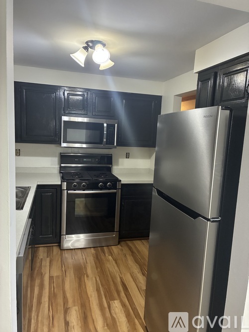 A kitchen with a stainless steel refrigerator, microwave, oven, and cabinets.