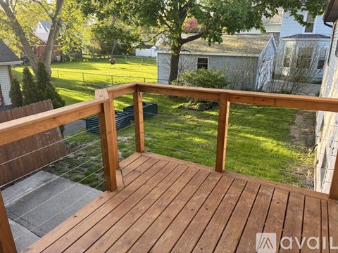 A wooden deck with a railing overlooking a grassy area.