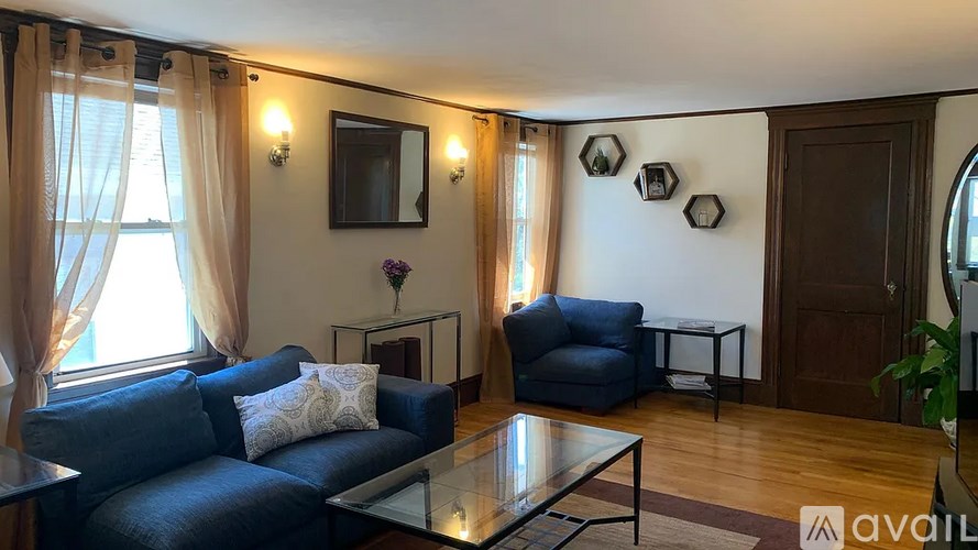 A living room with a blue couch and a glass coffee table.