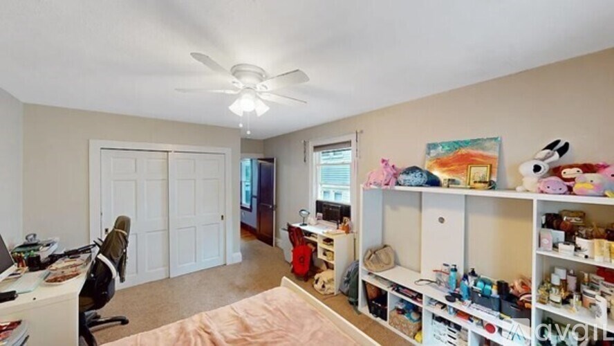 A room with a ceiling fan and a bed in the middle.