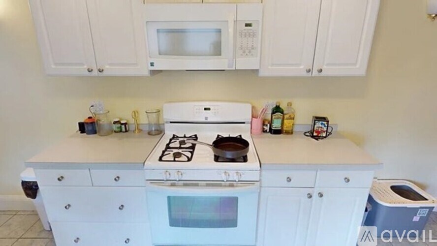A white kitchen with a stove, oven, microwave, and cabinets.