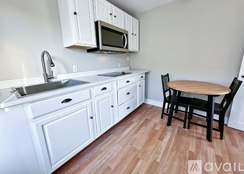 A kitchen with white cabinets and a wooden table.