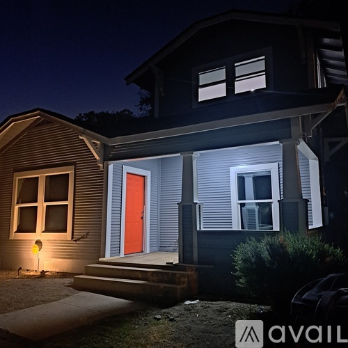 A house with a red door is illuminated by a single light source.