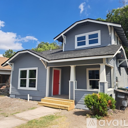 A grey house with a red door and a small porch.