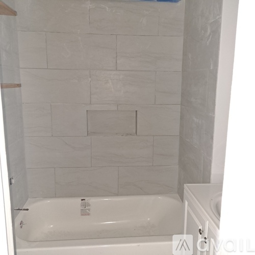 A white bathtub in a bathroom with white tiles.