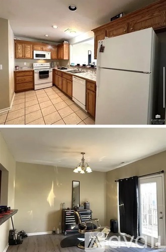 A kitchen with a white fridge and a living room with a black couch.