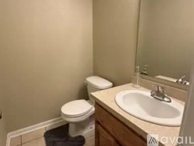 A bathroom with a toilet, sink, and mirror.