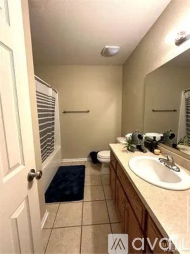 A bathroom with a sink, mirror, toilet, and a door.