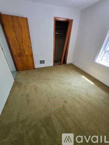 A room with a carpeted floor and a wooden door.