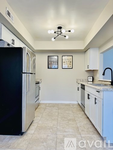 A kitchen with a black refrigerator and white cabinets.