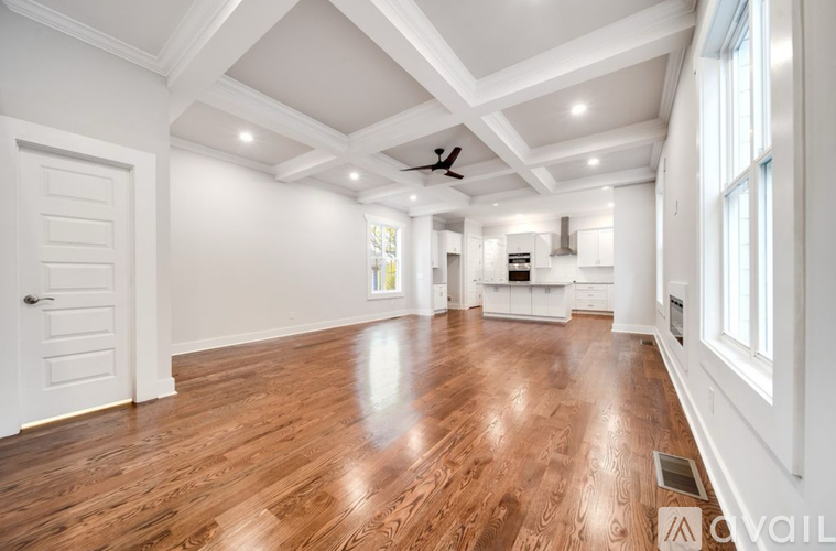 A spacious room with wooden floors and white walls.