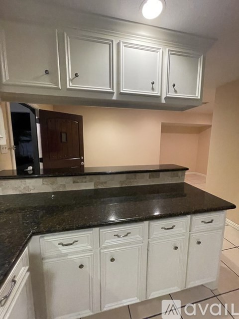 A kitchen with white cabinets and a black countertop.